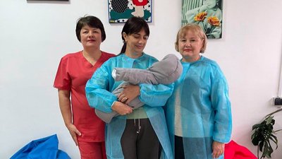 Жінка тримає у руках немовля, у якого з'явилися патронатні вихователі