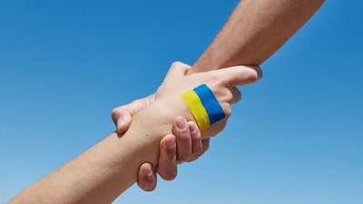 Рука допомоги з намальованим українським прапором