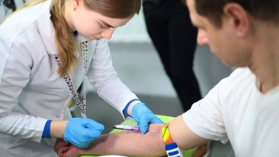 Медична працівниця бере кров у пацієнта для лабораторного аналізу