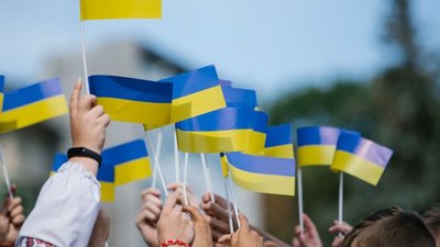 Люди на масовому заході тримають прапорці