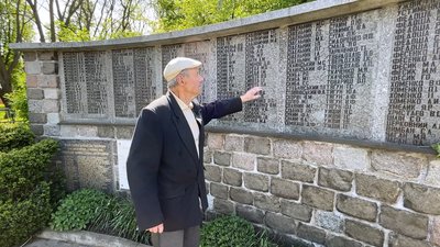 Житель Опішні Григорій Софієнко біля стіни із прізвищами полеглих під час Другої світової війни Житель Опішні Григорій Софієнко біля стіни із прізвищами полеглих під час Другої світової війни