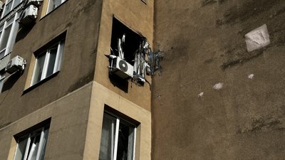 Розбите вікно внаслідок влучання російського дрона у вікно багатоповерхівки