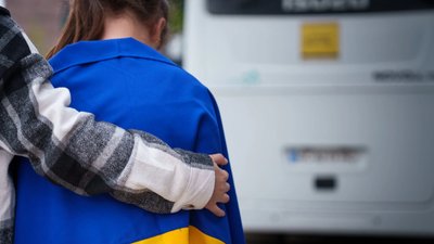 Дівчина з прапором України біля евакуаційного автобуса