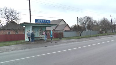 Люди чекають транспорт на зупинці в Щербанях