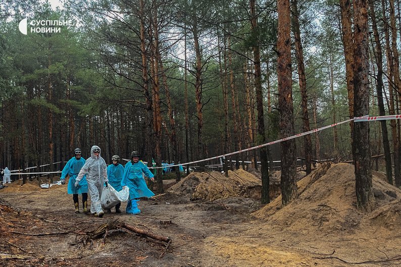 Слідчі виносять мішки з тілами в лісі поблизу Ізюма, де, після звільнення Силами оборони міста, виявили понад 440 могил. Харківщина, 16 вересня 2022 року